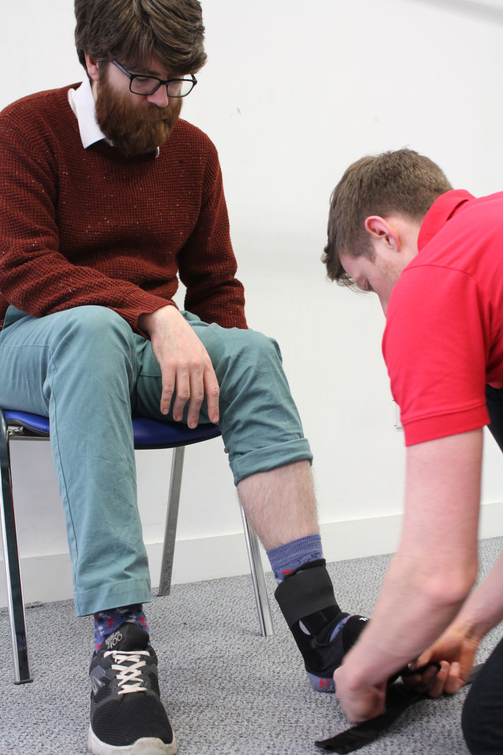 Man sat whilst Orthotics professional adjusts his angle support.