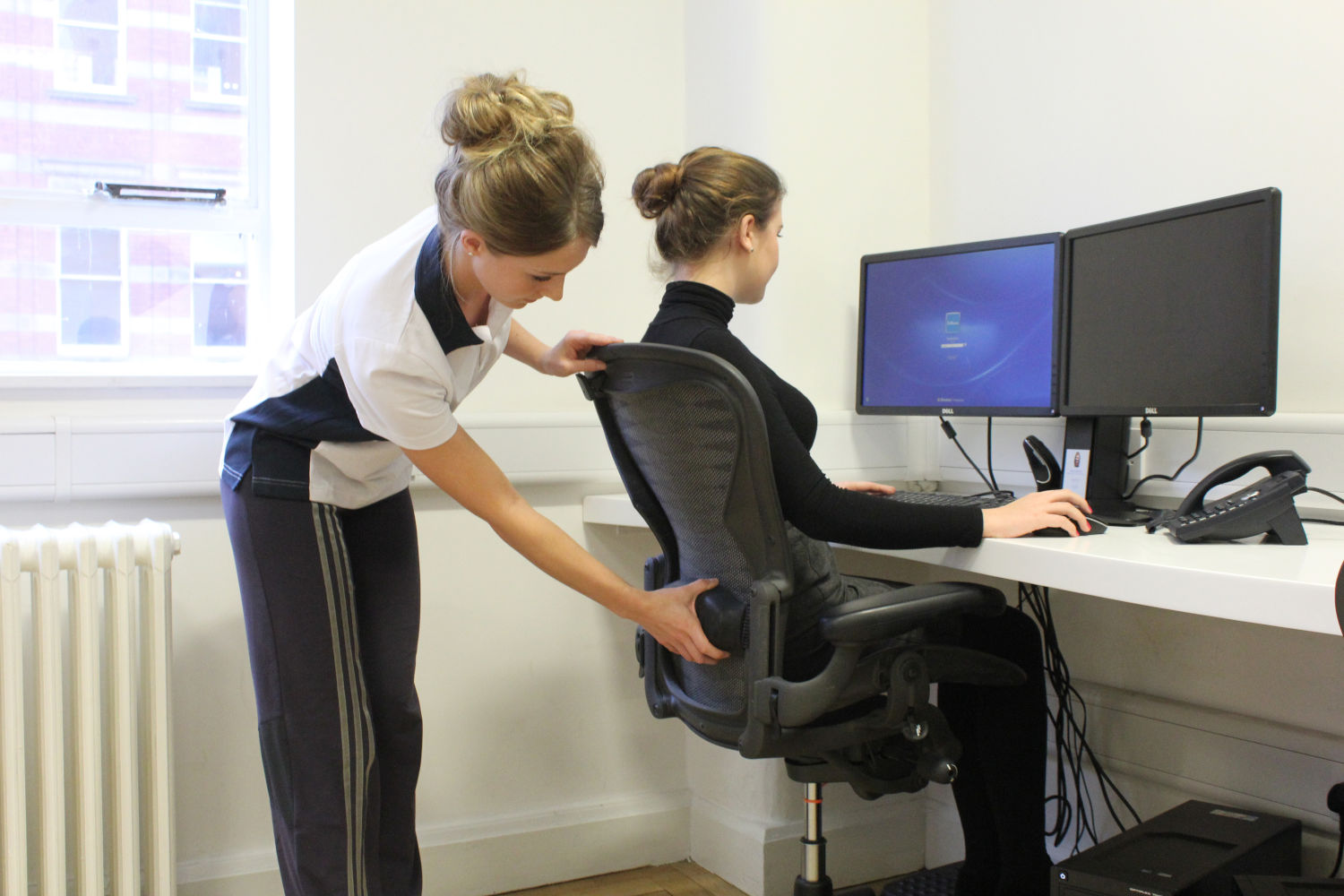 Admin staff member sat with good posture with support from Physio specialist.